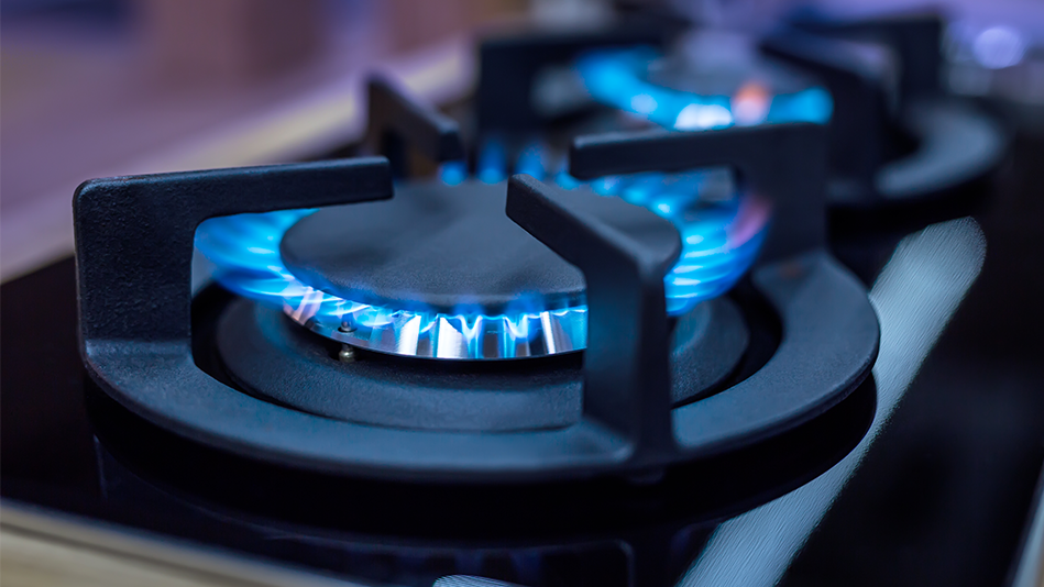 Blue flames circle a gas stove burner and grate