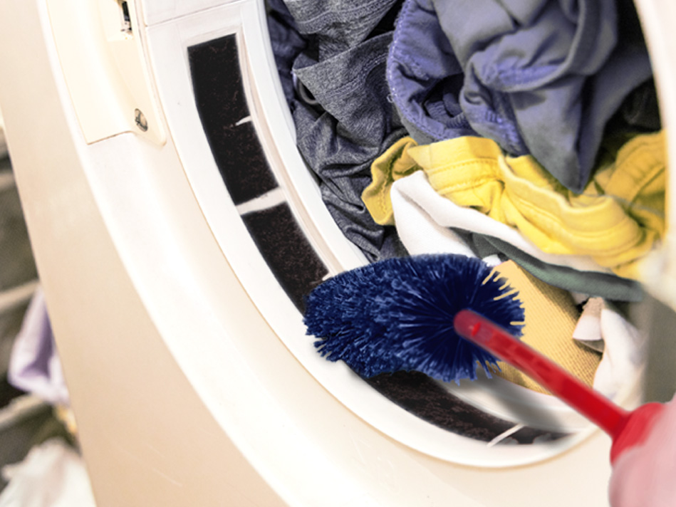 A blue dryer brush is used to clean the lint trap in a fully-loaded dryer