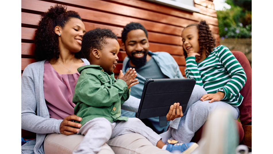 a black family of four shares a tablet while outside