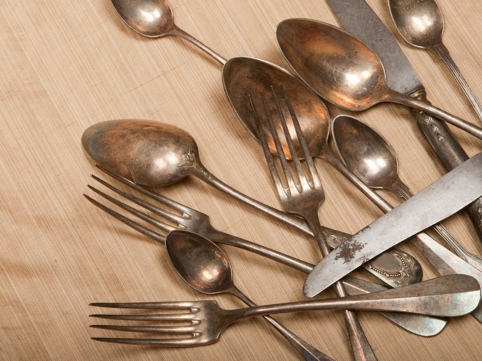 Rusted cutlery lie on tan, wood-look contact paper