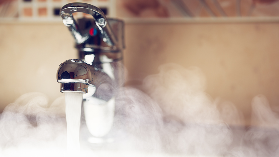 A faucet at full blast spouts hot water, creating vapor