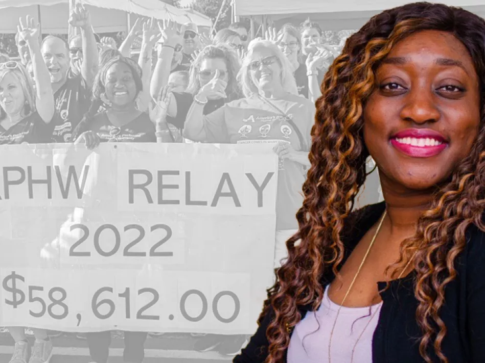 A black woman with long hair smiles in front of her achievement of raising nearly $60K for Relay for Life